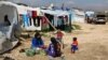 FILE - Syrian women prepare food for their family outside their tents at a Syrian refugee camp in the town of Bar Elias in Lebanon's Bekaa Valley, March 29, 2016. 