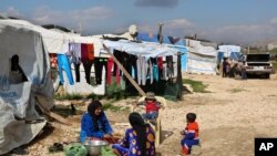 Syrian women prepare food for their family outside their tents, at a Syrian refugee camp in the town of Bar Elias, in Lebanon's Bekaa Valley, March 29, 2016. 