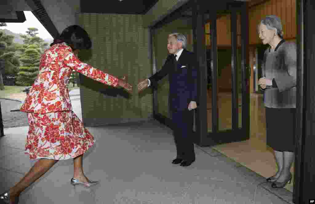 U.S. First Lady Michelle Obama recovers from a stumble before shaking hands with Japanese Emperor Akihito, center, as Empress Michiko looks on upon her arrival at the Imperial Palace in Tokyo.