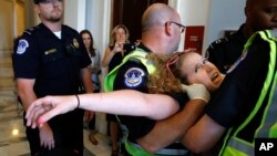 Stephanie Woodward, de Rochester, Nueva York, que padece de espina bífida y usa silla de ruedas, es sacada de una protesta frente a las oficinas del líder de la mayoría del Senado, Mitch McConnell, el jueves 22 de junio en el Capitolio.