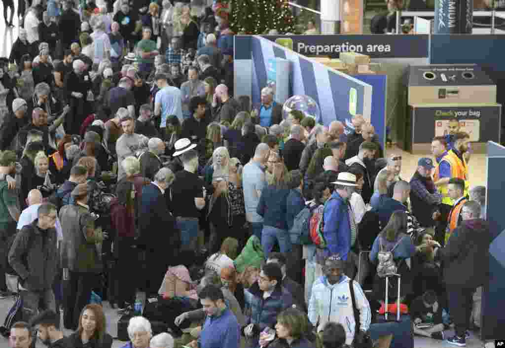 Passengers wait near the departures gate at Gatwick airport, near London, England, as the airport remains closed with incoming flights delayed or diverted to other airports, after drones were spotted over the airfield last night and this morning.