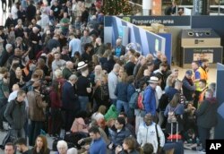 FILE - People wait near the departures gate at Gatwick airport, near London, as the airport remains closed with incoming flights delayed or diverted to other airports, after drones were spotted over the airfield, Dec. 20, 2018.