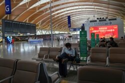 Penumpang yang mengenakan masker beristirahat di Bandara Internasional Pudong di Shanghai, China pada 25 Juli 2021. (Foto: AP)