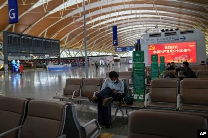 Penumpang yang mengenakan masker beristirahat di Bandara Internasional Pudong di Shanghai, China pada 25 Juli 2021. (Foto: AP)