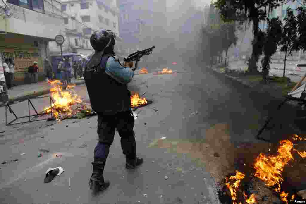 A police officer shoots rubber bullets during a clash with activists of Hifazat-e-Islam in front of the national mosque in Dhaka, May 5, 2013.