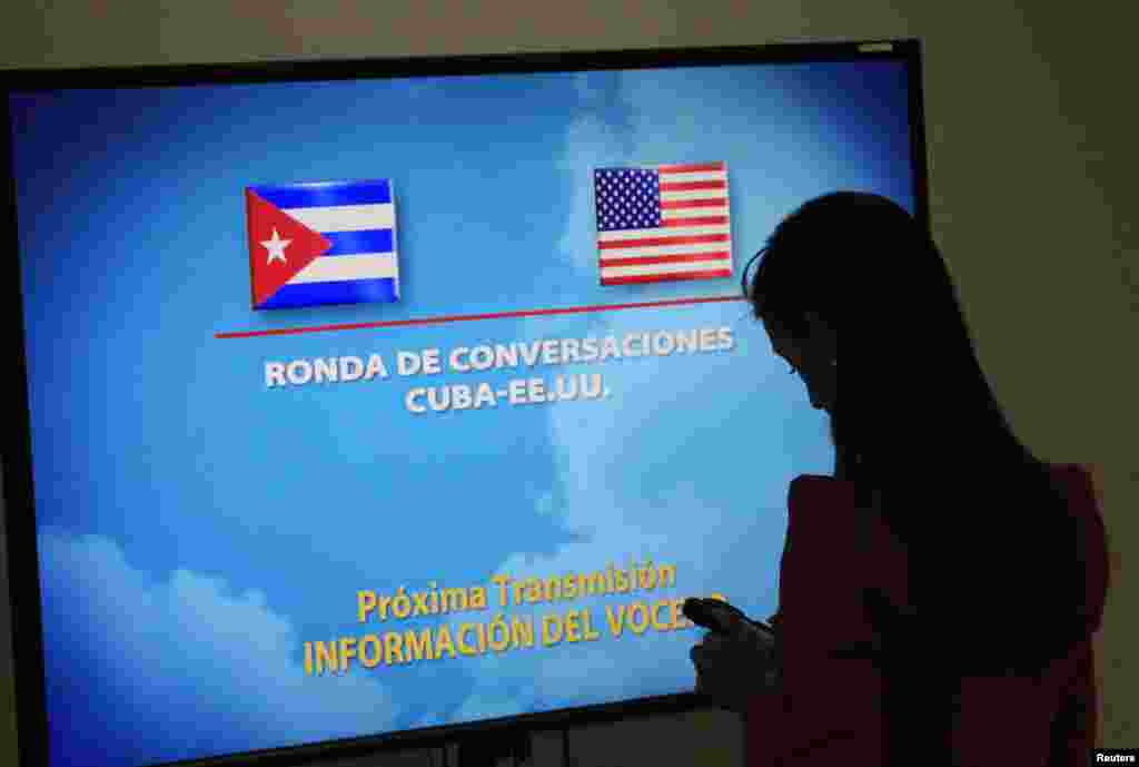 A journalist stands near a screen announcing a round of negotiations between Cuba and the U.S. in Havana, Jan. 22, 2015.