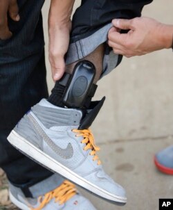 A parole agent inspects the global positioning device worn by a paroled sex offender in Sacramento, Calif., Dec. 1, 2015.