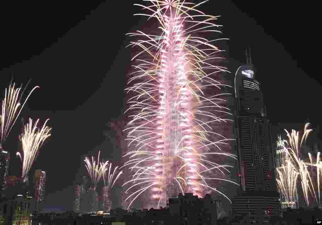 Letusan kembang api di Burj Khalifa, gedung tertinggi di dunia, dan pencakar-pencakar langit di sekitarnya untuk menandai Tahun Baru di Dubai, Uni Emirat Arab (1/1). (AP/Jon Gambrell)