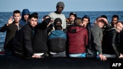 Les migrants réagissent alors que le bateau de sauvetage du MV Aquarius s'approche de leur bateau en caoutchouc à quelque 50 kilomètres de la côte libyenne le 12 mai 2018.