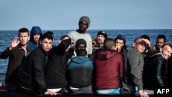 Les migrants réagissent alors que le bateau de sauvetage du MV Aquarius s'approche de leur bateau en caoutchouc à quelque 50 kilomètres de la côte libyenne, le 12 mai 2018.