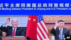 In this photo released by Xinhua News Agency, Chinese President Xi Jinping, right, and U.S. President Joe Biden appear on a screen as they hold a meeting via video link, in Beijing, China, Nov. 16, 2021. 