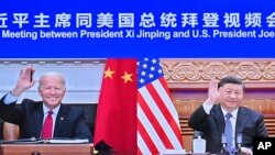 In this photo released by Xinhua News Agency, Chinese President Xi Jinping, right, and U.S. President Joe Biden appear on a screen as they hold a meeting via video link, in Beijing, China, Nov. 16, 2021. 