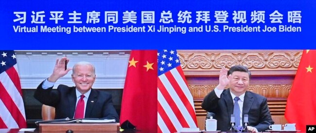 In this photo released by Xinhua News Agency, Chinese President Xi Jinping, right, and U.S. President Joe Biden appear on a screen as they hold a meeting via video link, in Beijing, China, Nov. 16, 2021.
