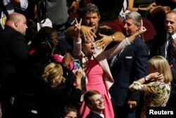 People in the crowd try to block anti-war protestor Alli McCracken, center, of the "Code Pink" activist group during the opening session of the Republican National Convention in Cleveland, Ohio, July 18, 2016.