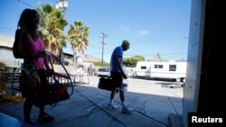 FILE - A Parkinson's patient (R) makes his way home after working out with a trainer in Costa Mesa, California.