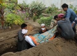 Gayesh Ansari, memandang tubuh istrinya yang hamil delapan bulan, Gulshan Ansari, yang meninggal karena COVID-19 saat akan dimasukkan liang lahat di sebuah pemakaman di Mumbai, India 28 April 2021. (REUTERS)