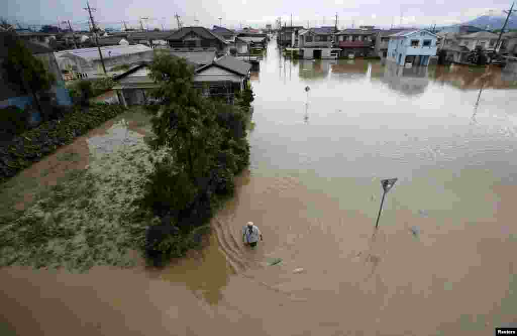 A man wades through a residential area flooded by the Kinugawa river, caused by typhoon Etau, in Joso, Ibaraki prefecture, Sept. 10, 2015.