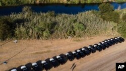 FILE - A line of Texas Department of Safety vehicles lines the bank of the Rio Grande near an encampment of migrants, many from Haiti, Sept. 22, 2021, in Del Rio, Texas. 