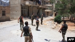 FILE - Syrian army soldiers patrol a street in government-controlled Aleppo's al-Khalidiya area where the army progressed towards the industrial zone of al-Layramoun and Bani Zeid on June 28, 2016.