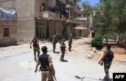 FILE - Syrian army soldiers patrol a street in government-controlled Aleppo's al-Khalidiya area where the army progressed toward the industrial zone of al-Layramoun and Bani Zeid, June 28, 2016.