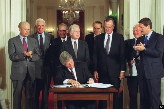 FILE - U.S. President Bill Clinton signs side deal of the three-nation North American Free Trade Agreement (NAFTA) at the White House, Washington, D.C., Tuesday, Sept. 14, 1993. (AP Photo/Ron Edmonds)