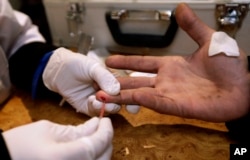 FILE - In this photo Nov. 21, 2012 file photo, a doctor takes an AIDS/HIV blood test from a drug user in a mobile laboratory in Odessa, Ukraine.