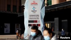 Pedestrians walk past a countdown clock for the Beijing 2022 Winter Olympic Games in Beijing, China, Dec. 7, 2021.
