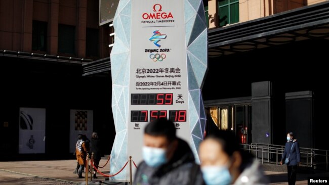 Pedestrians walk past a countdown clock for the Beijing 2022 Winter Olympic Games in Beijing, China, Dec. 7, 2021.
