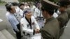 FILE - Korean-American taekwondo grandmaster Jung Woo-jin, center, shakes hands with North Korean border soldiers as he offers a peace gesture of taekwondo "dobok" robes on the North Korean side of the DMZ line outside Panmunjom, May 19, 2006.