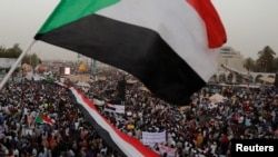 FILE - Thousands of protesters wave Sudanese flags, hold banners and chant slogans during a demonstration in front of the Defense Ministry in Khartoum, Sudan, April 18, 2019. 