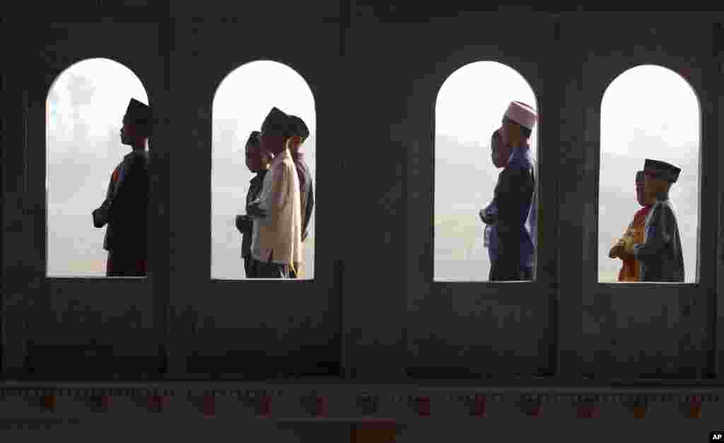 Muslim youths are seen through the windows of a mosque as they perform Eid al-Fitr morning prayers, Porong, East Java, Indonesia, August 8, 2013. 