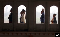 FILE - Muslim youths are seen through the windows of a mosque as they perform Eid al-Fitr morning prayers, Porong, East Java, Indonesia, August 8, 2013.