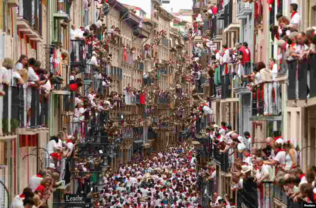 Orang-orang menonton dari balkon dalam festival San Fermin atau lari bersama-sama dikejar banteng di kota Pamplona, Spanyol.