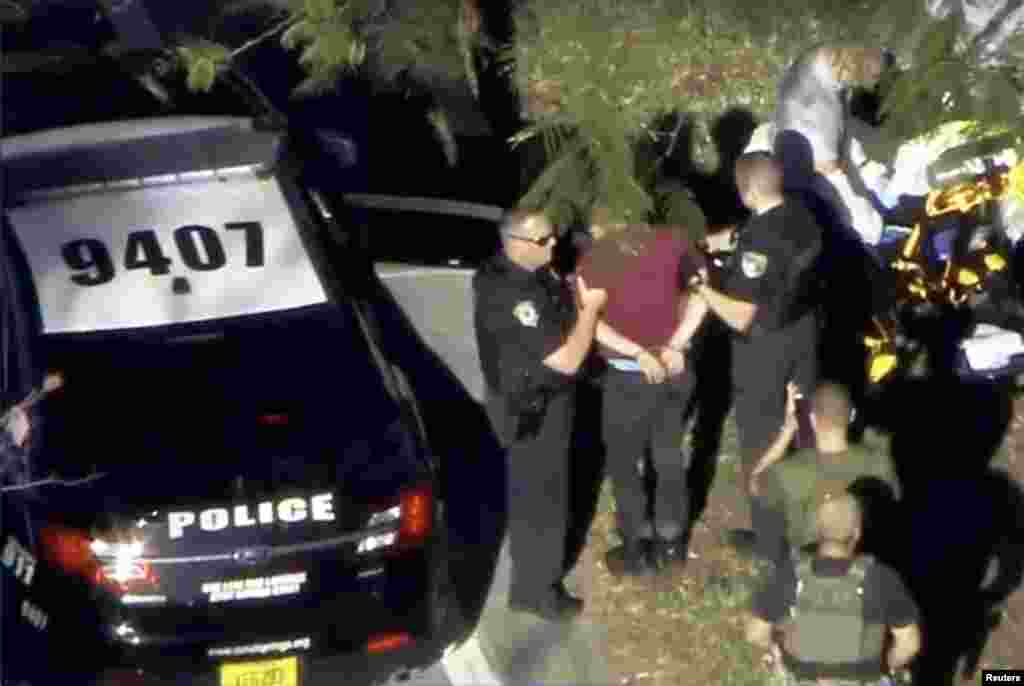 A man placed in handcuffs is led by police near Marjory Stoneman Douglas High School following a shooting incident in Parkland, Feb. 14, 2018 in a still image from video.