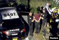 A man placed in handcuffs is led by police near Marjory Stoneman Douglas High School following a shooting incident in Parkland, Florida, Feb. 14, 2018 in a still image from video.