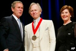 FILE - President George W. Bush, Tom Wolfe and first lady Laura Bush are pictured at the National Endowment for the Arts national medal awards ceremony at Constitution Hall in Washington, April 22, 2002. Wolfe was a recipient of the National Humanities Medal. He died May 14, 2018, at a New York City hospital at age 88.