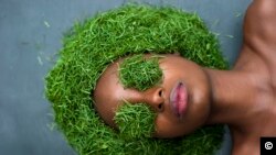Jeune femme dont la tête et les yeux sont couverts de gnetum africanun (m-fumbu, coco), légume très consommé au Congo et dans la sous-région.