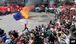 Un manifestante corre alrededor de una efigie en llamas del presidente Rodrigo Duterte durinte una manifestación del Día de los Trabajadores en Manila, Filipinas, el miércoles, 1 de mayo de 2019.