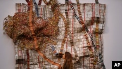 L'employé d'une Sotheby's regarde une sculpture créée par El Anatsui du Ghana à la vente d'art africain moderne et contemporain de Sotheby's à Londres, le 12 mai 2017