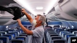 In this May 28, 2020, file photo, a passenger wears personal protective equipment on a Delta Airlines flight after landing at Minneapolis−Saint Paul International Airport, in Minneapolis. (AP Photo/John Minchillo, File)