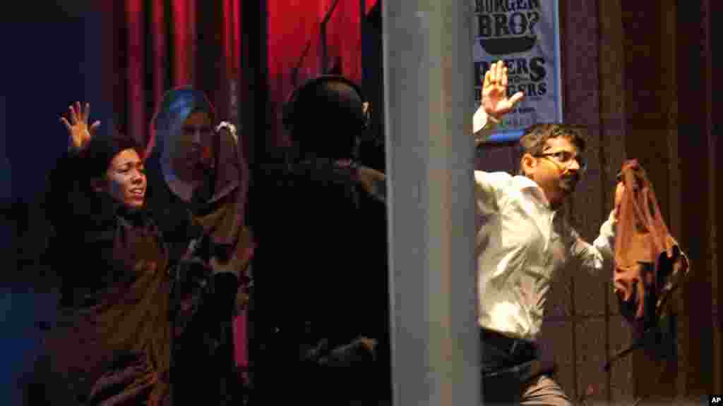 Hostages run towards armed tactical response police as they run to freedom from a cafe under siege at Martin Place in the central business district of Sydney, Australia, Dec. 16, 2014. 