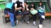 FILE - South Korean middle school students use their smartphones at a bus station in Seoul, South Korea, May 15, 2015.
