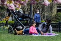 People wear masks while enjoying Washington Square Park Tuesday, April 21, 2020, in New York.