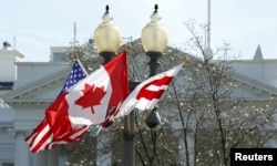 A Canadian flag flutters between a U.S. flag and a Washington, D.C., flag in front of the White House in Washington, March 7, 2016. Preparations are under way for the official state visit of Canada's Prime Minister Justin Trudeau on Thursday.