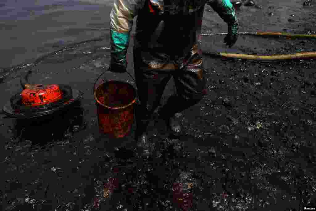 A worker cleans up an oil spill following an underwater volcanic burst in Tonga, in Ancon, Peru, Jan. 25, 2022.