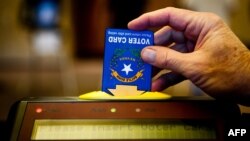 A poll worker inserts an electronic voting card into a machine in Sparks, Nevada, Nov. 6, 2012.