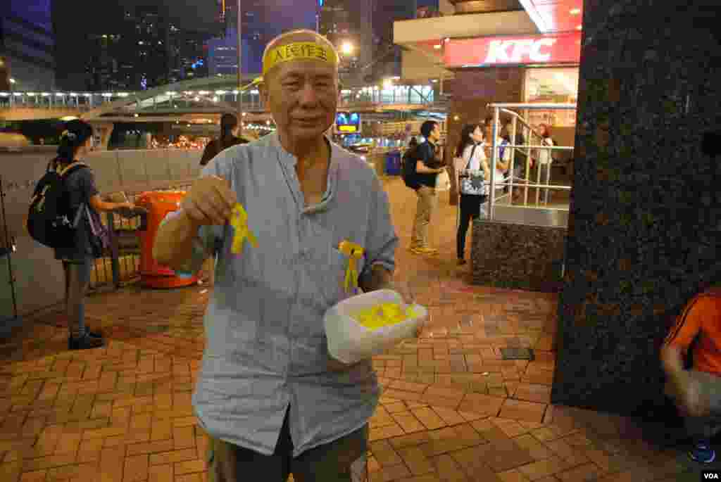 年約70歲的香港市民黃伯伯在前往罷課集會場地添馬公園的主要通路，向途人派發代表真普選的黃絲帶