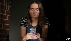 In this Monday, July 22, 2019 photo, Rachel Whalen looks at her phone at her home in Draper, Utah. Whalen remembers feeling gutted in high school when a former friend would mock her online postings, threaten to unfollow or unfriend her on social media and