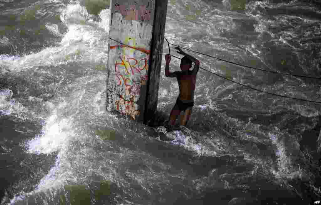 Seorang anak laki-laki bermain di bawah jembatan di Manila, Filipina, usai topan Sarika melanda Pulau Luzon di sana.