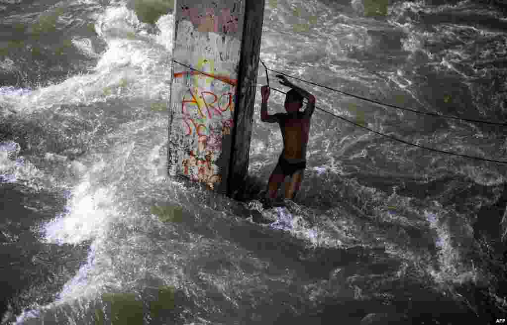 A boy plays in a swollen creek under a bridge in Manila,Philippines. Typhoon Sarika lashed the main Philippine island of Luzon, flattening homes and toppling trees and power pylons as more than 12,000 people fled to safer ground, officials said. Shanties built beside a river, under a creek are the usual victims of floodings.&nbsp;